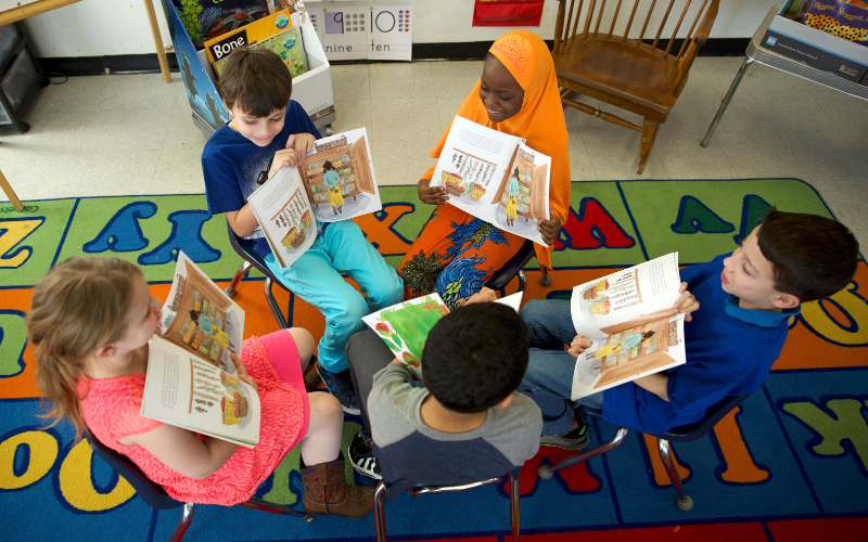 Fountas & Pinnell Book Club photo of five students seated in chairs discussing a book