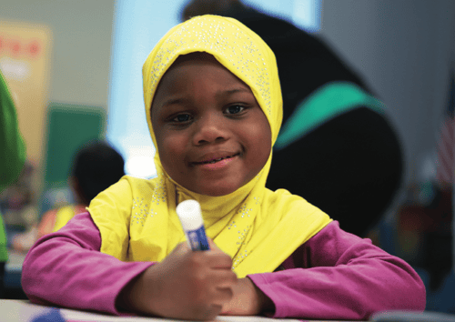 Leading for Literacy Blog Element Young Student holding a marker looking at camera