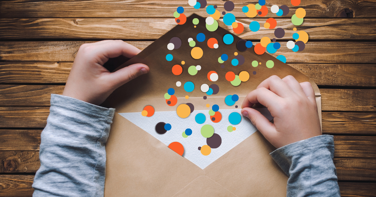 A photo of an envelope on a table with children's hands and digital colored confetti
